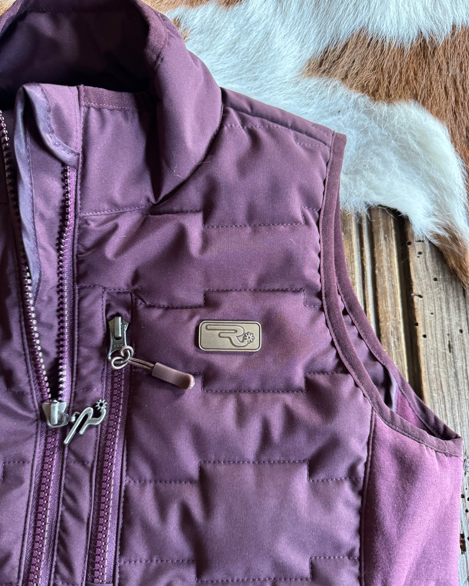 Purple quilted jacket with a brand logo on a textured surface