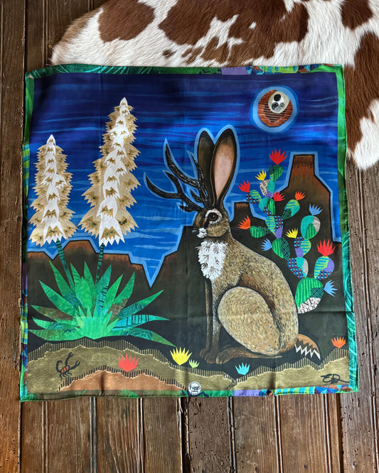 Decorative scarf with a jackalope and nature design on a wooden surface