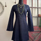 Navy blue dress on a mannequin with necklaces against a neutral wall.
