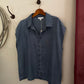 Blue denim shirt on a hanger against a beige wall.