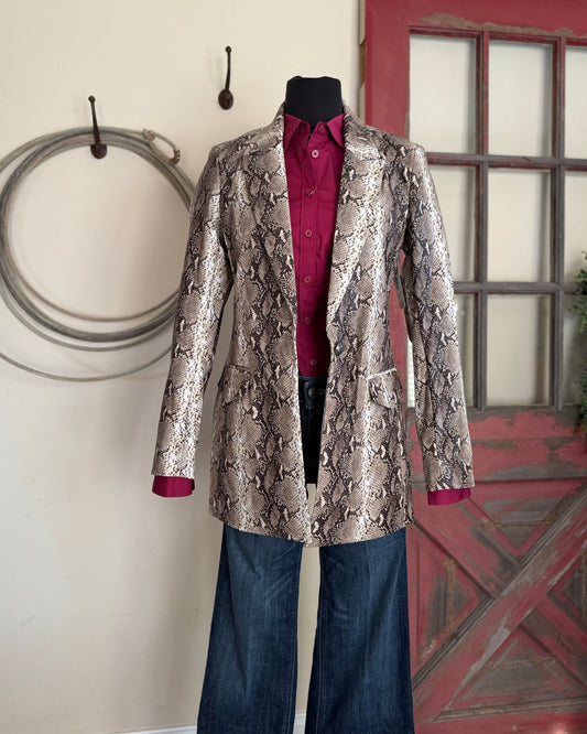 Mannequin wearing a patterned jacket and jeans against a rustic background with a red door and wooden wall.