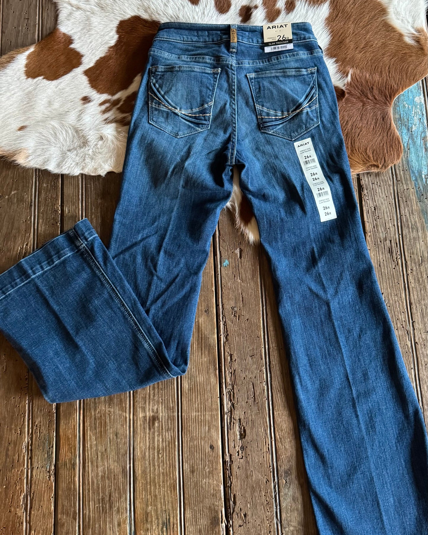 Blue jeans with a brand tag on a wooden floor and cowhide rug