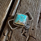 A square turquoise and silver twilly slide resting on a weathered, rustic wooden surface.