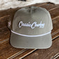 Green cap with 'Classic Cowboy' text on a wooden surface with cowhide rug in the background