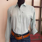 Person wearing a light green shirt and blue jeans with a brown belt, standing indoors.