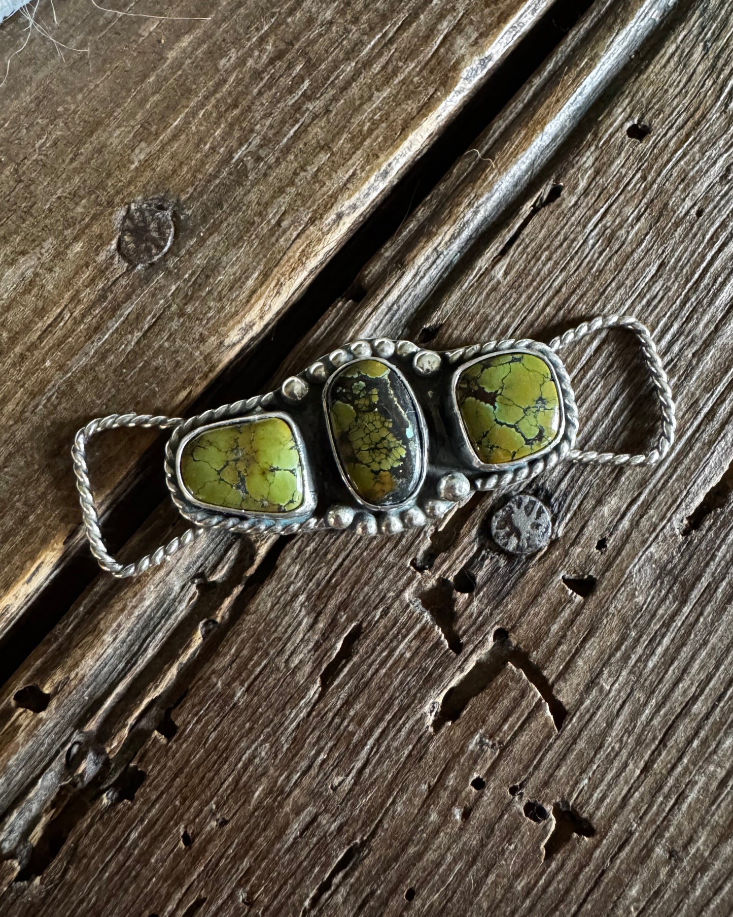 Twilly slide with three green stones on a wooden surface