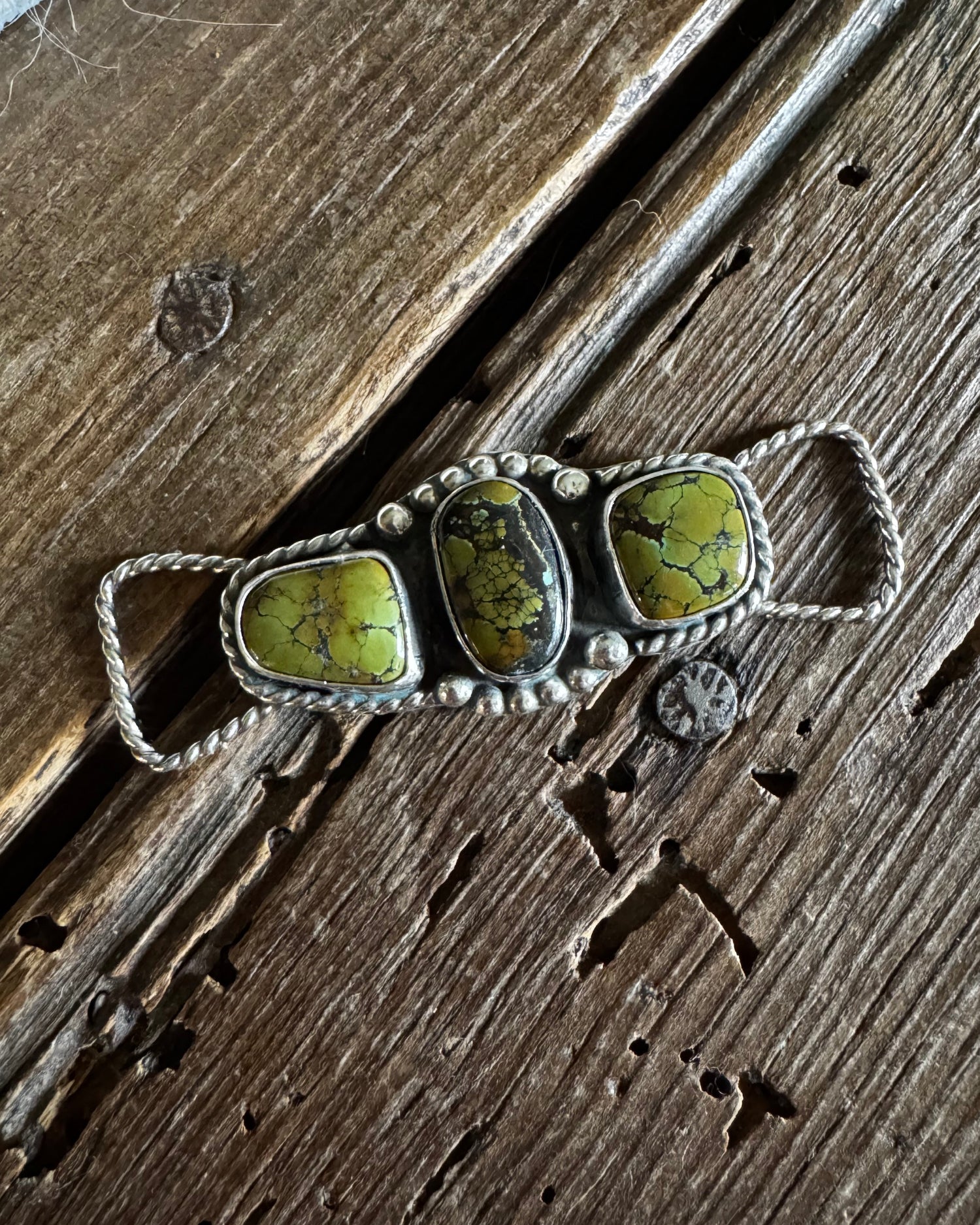 Twilly slide with three green stones on a wooden surface
