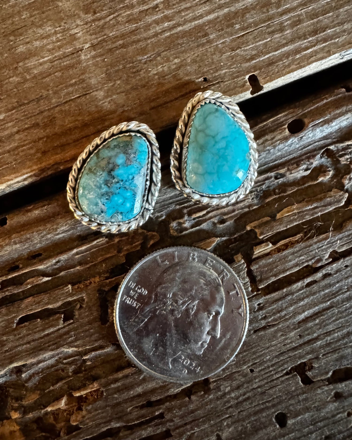 Turquoise stone earrings next to a quarter on wooden surface