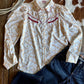 White shirt with red patterns and blue jeans on a wooden surface