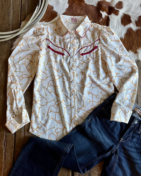 White shirt with red patterns and blue jeans on a wooden surface