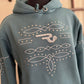 blue hoodie with decorative patterns on a mannequin against a neutral background