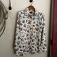 Floral patterned shirt hanging on a hook against a white wall.