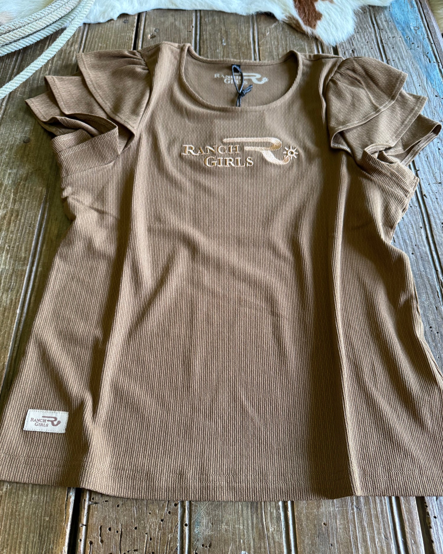 Brown t-shirt with a logo on a wooden surface