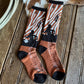 Pair of patterned socks on a wooden surface with a cowhide rug.