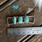Silver ring with turquoise stones on a wooden surface with a ruler for scale.