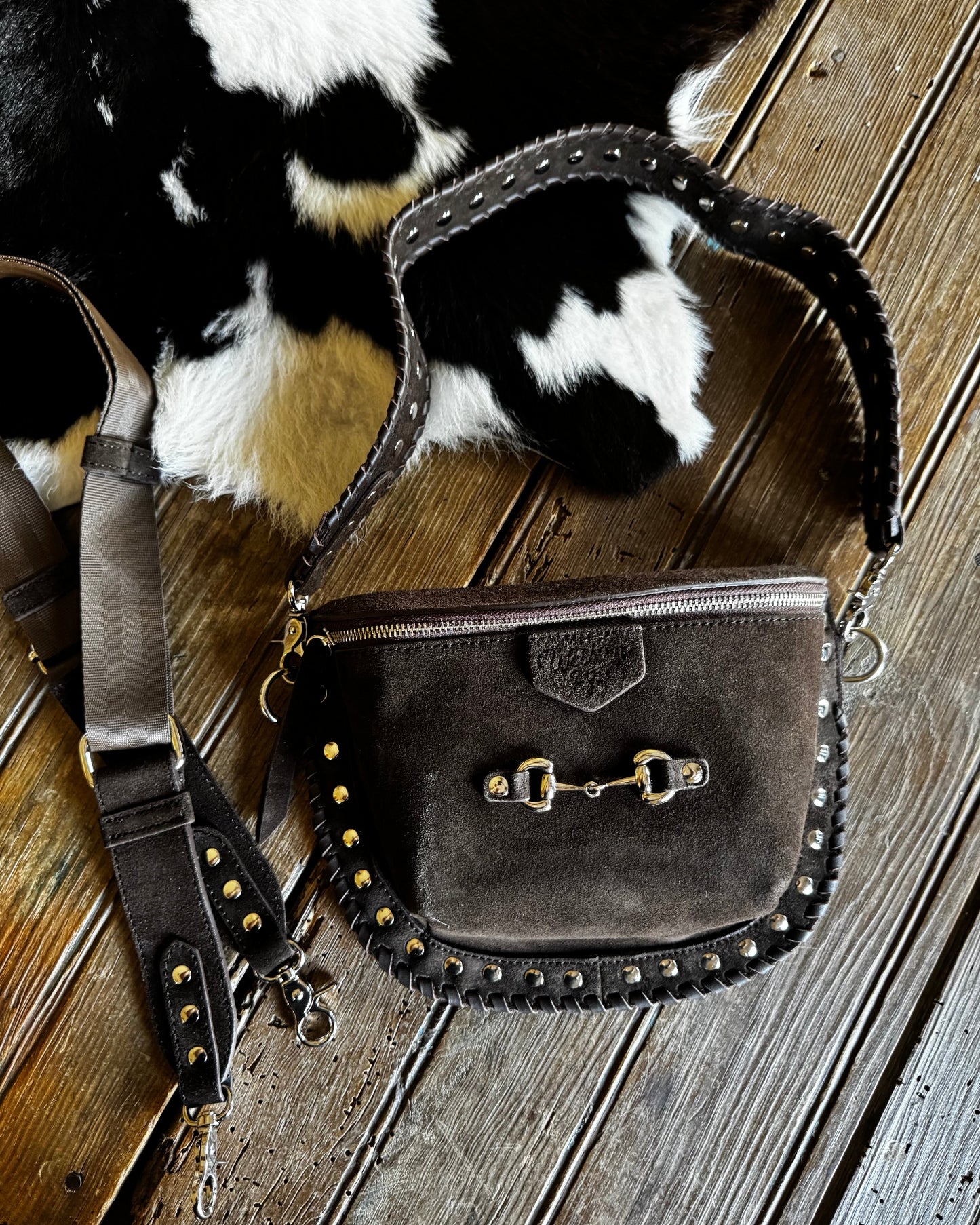 Brown leather bag with gold studs on a wooden surface