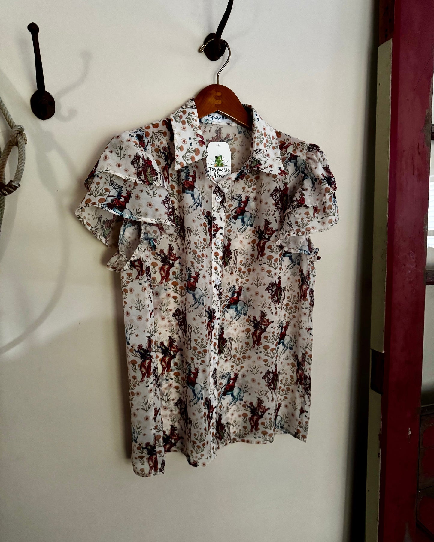 Floral patterned shirt hanging on a hook against a white wall.