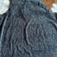 black tank top with white boot stitch pattern on a brown and white cowhide rug