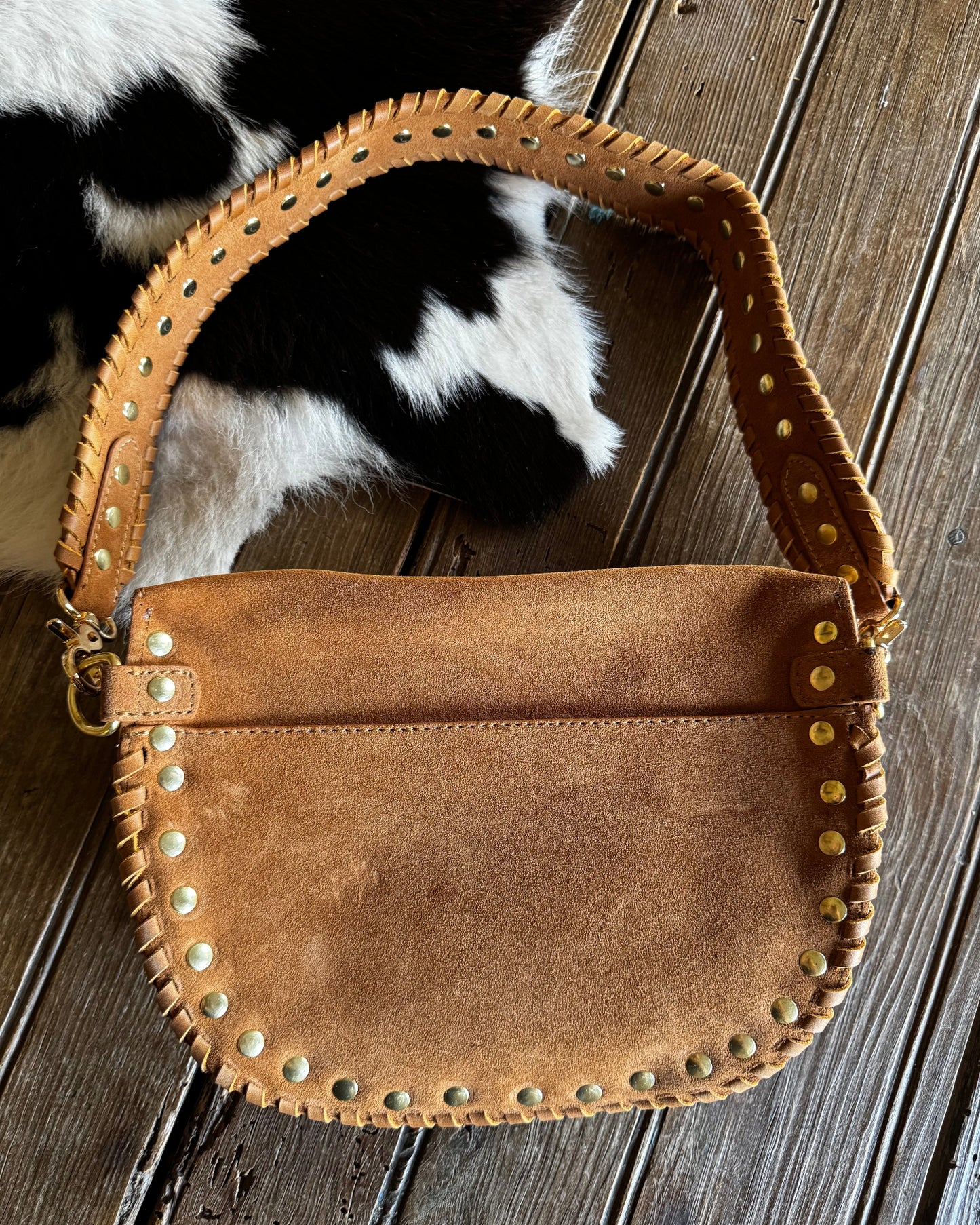 Brown leather handbag with studs on a wooden surface