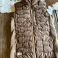 Brown quilted vest on a wooden surface with cowhide rug