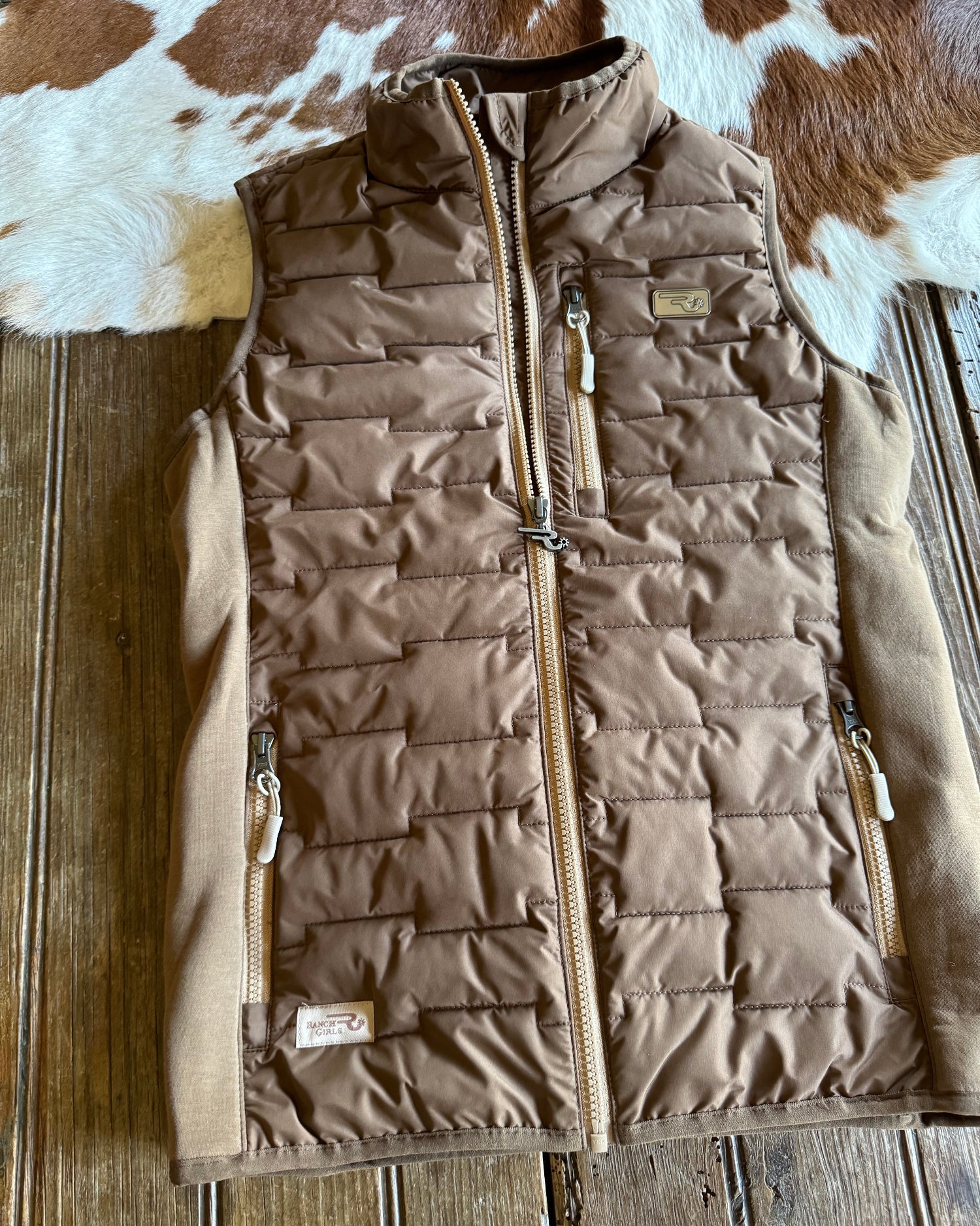 Brown quilted vest on a wooden surface with cowhide rug