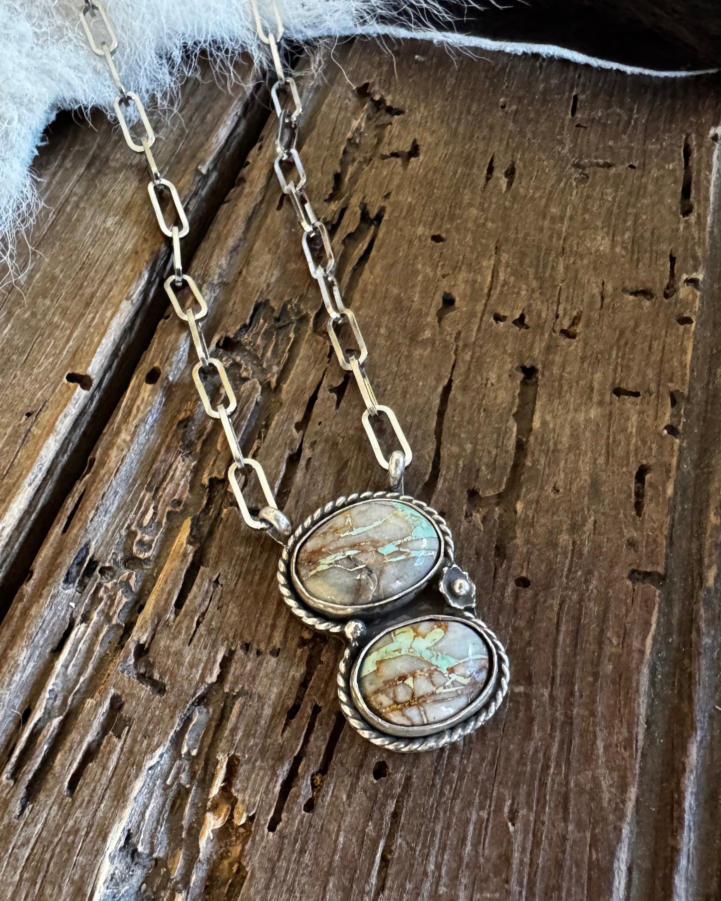 Necklace with two circular pendants on a wooden surface