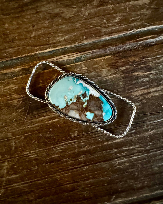 Turquoise stone in a silver frame on a wooden surface