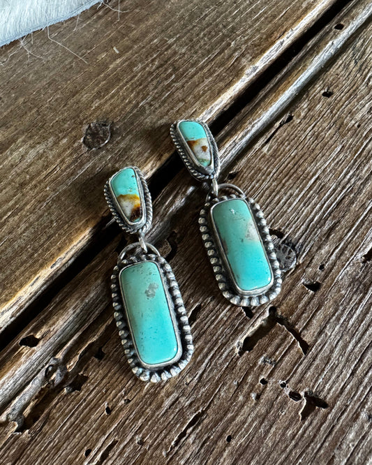 Turquoise earrings on a wooden surface