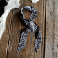 Black and white checkered bandana with paisley patterns on a wooden surface