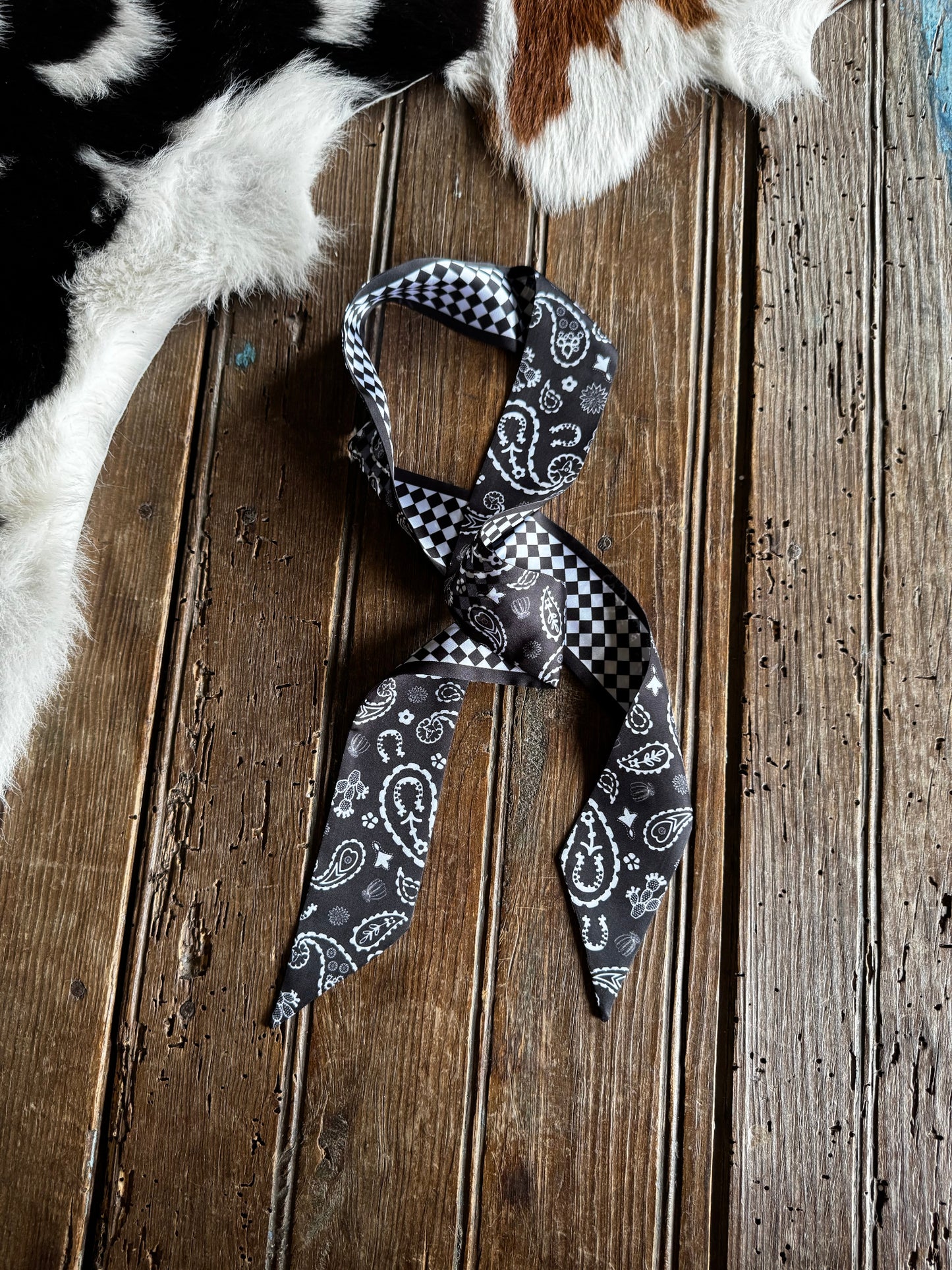 Black and white checkered bandana with paisley patterns on a wooden surface