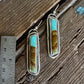 Pair of earrings with turquoise and amber stones on a wooden surface with a ruler for scale.