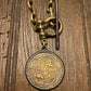 Vintage gold chain with a decorative coin on a wooden surface
