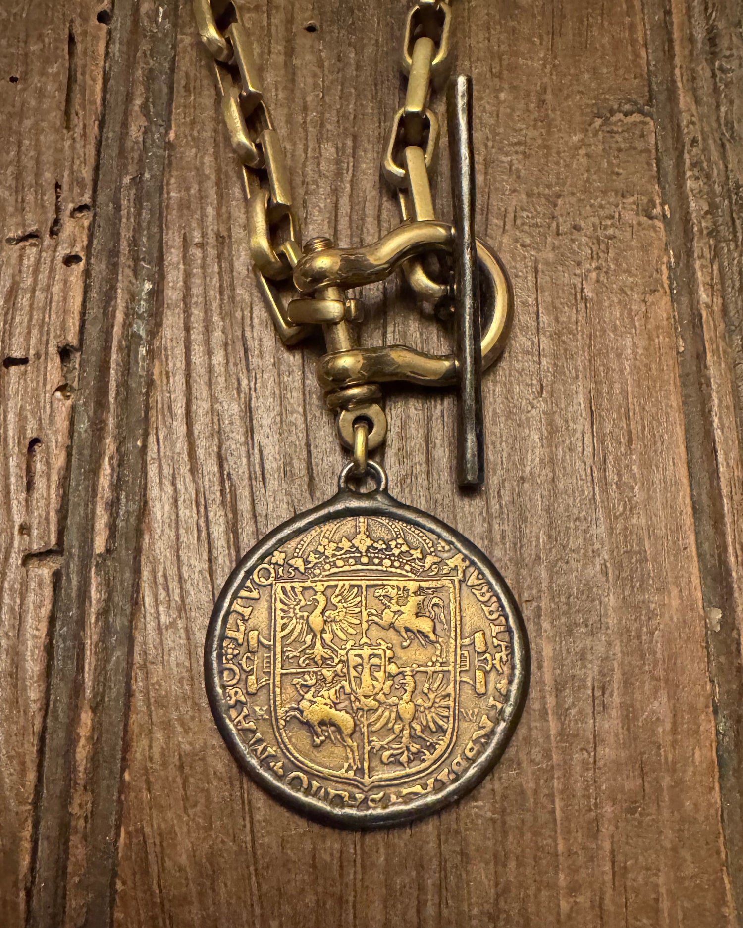 Vintage gold chain with a decorative coin on a wooden surface