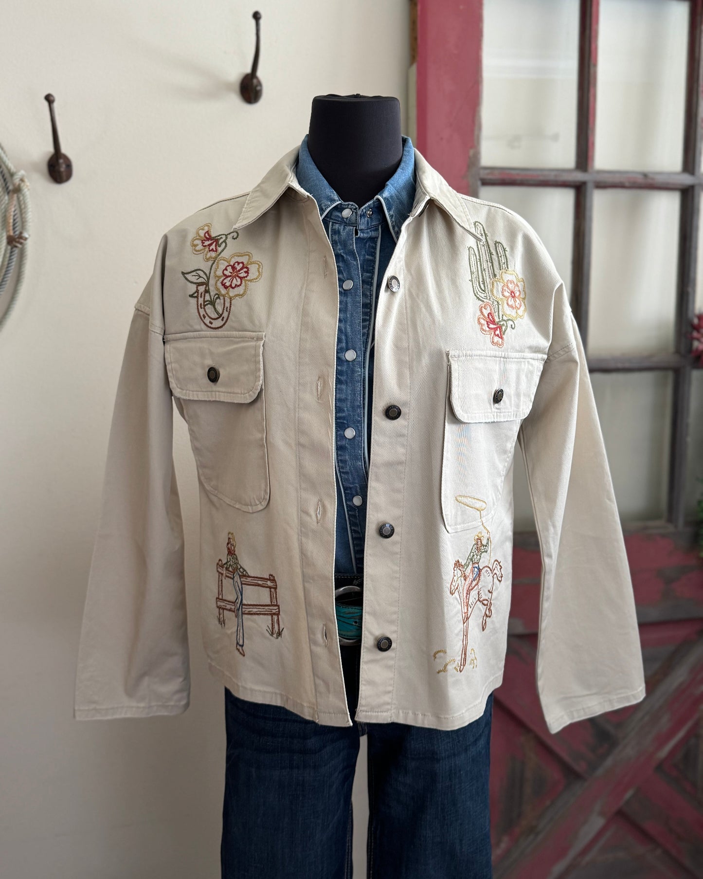 Beige embroidered jacket on a mannequin against a neutral background