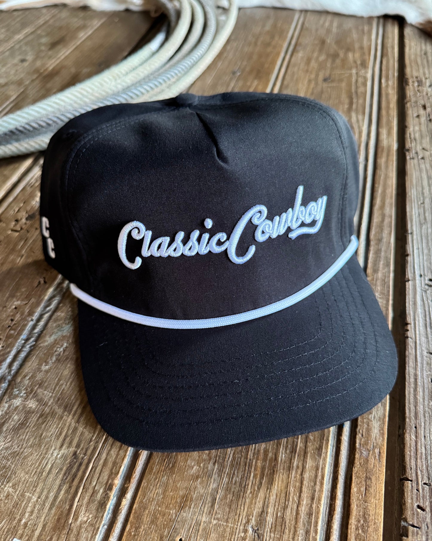 Black cap with 'Classic Cowboy' embroidery on a wooden surface