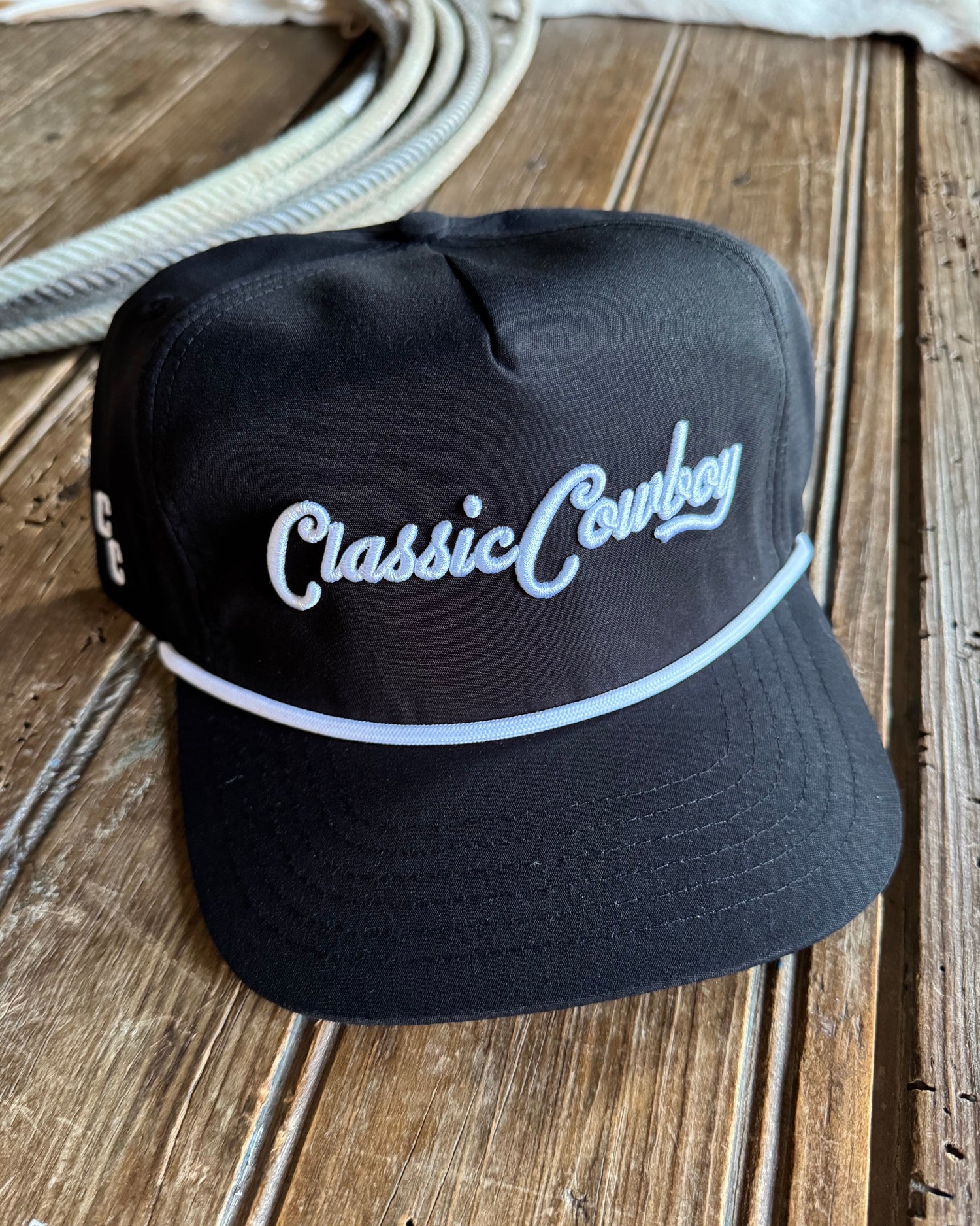 Black cap with 'Classic Cowboy' embroidery on a wooden surface