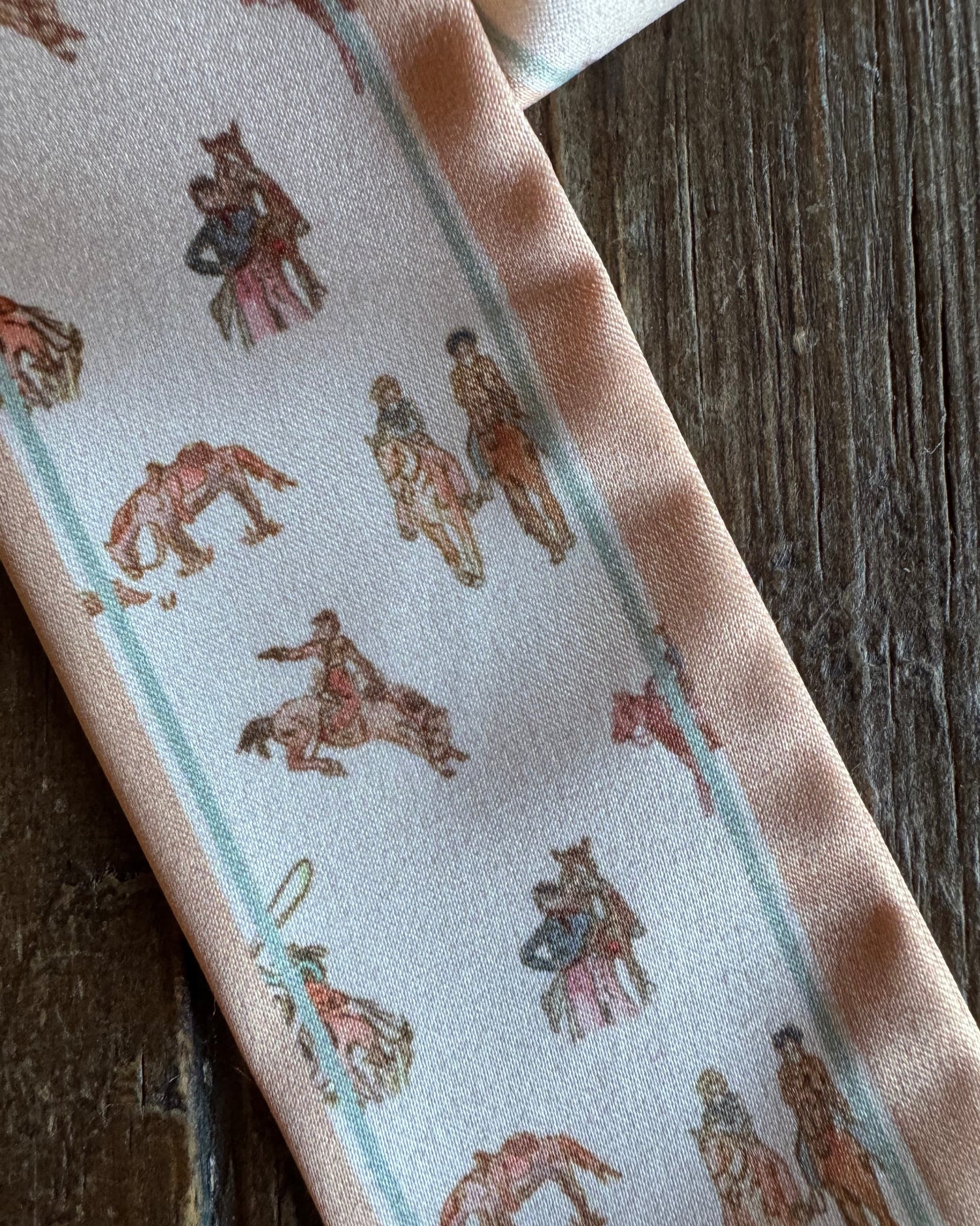 Close up of ribbon scarf with cowboys on rustic wooden background