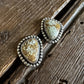 Pair of earrings with textured stones on a wooden surface