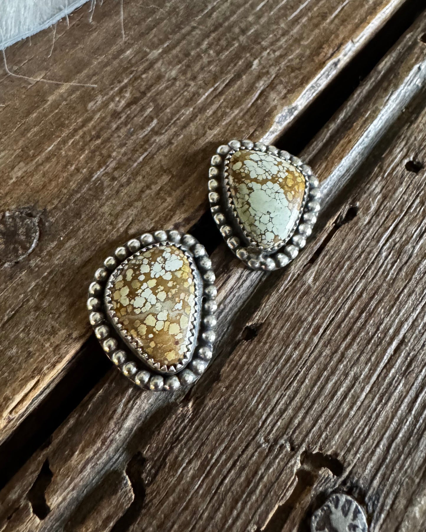 Pair of earrings with textured stones on a wooden surface
