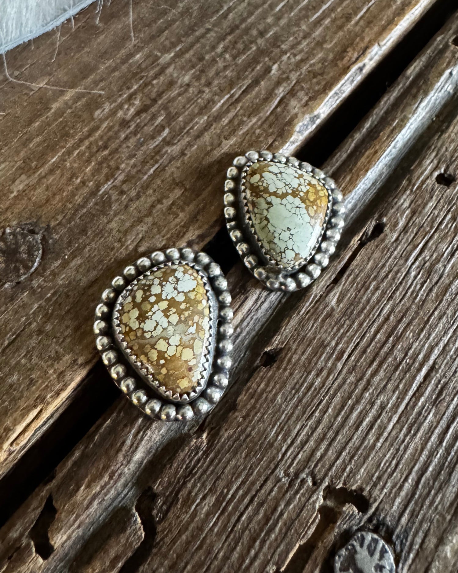 Pair of earrings with textured stones on a wooden surface