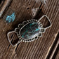Silver pendant with turquoise stone on a wooden surface with white fur
