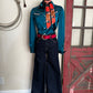 Pair of dark blue pants with a red belt and turquoise blouse with a white background and red door. 