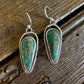 Pair of green stone earrings on a wooden surface