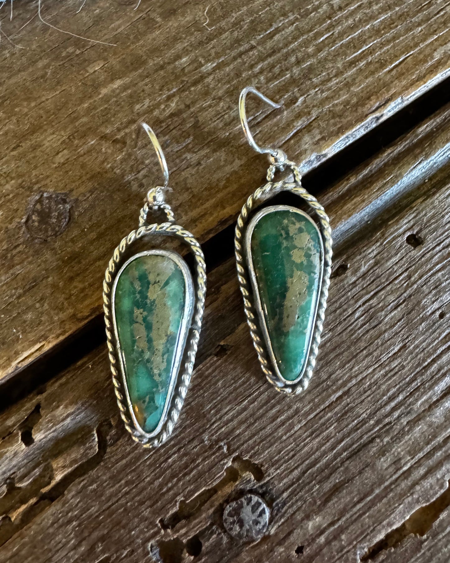 Pair of green stone earrings on a wooden surface