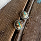 Pair of silver earrings with embedded stones on a wooden surface