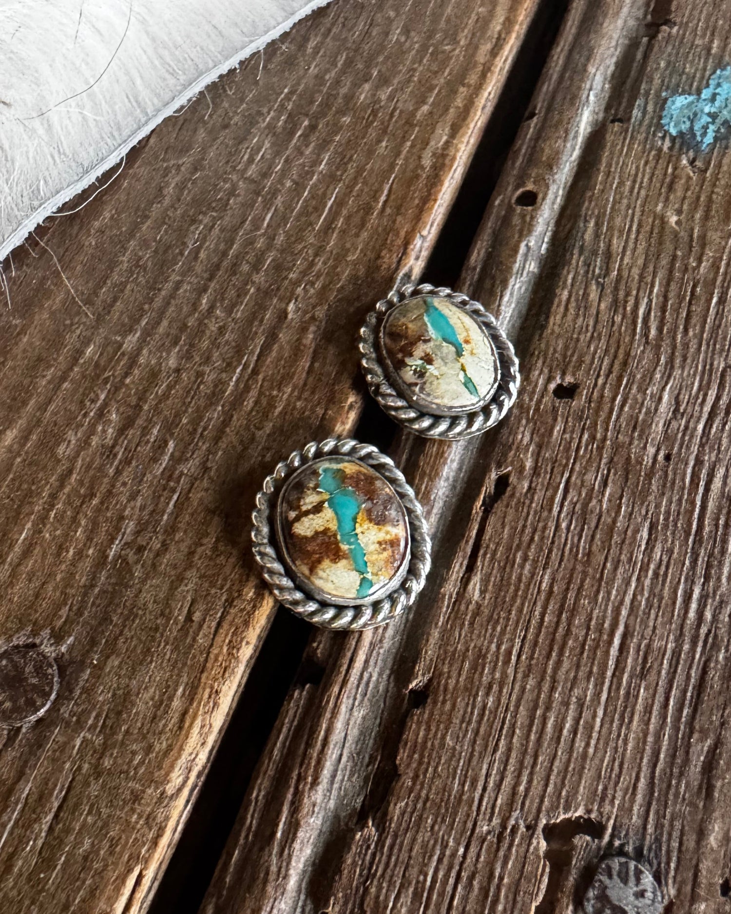 Pair of silver earrings with embedded stones on a wooden surface