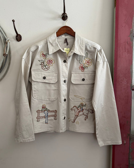Embroidered jacket hanging on a wall with a wooden hanger.