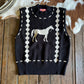 Black sweater vest with horse design on a wooden surface with cowhide rug
