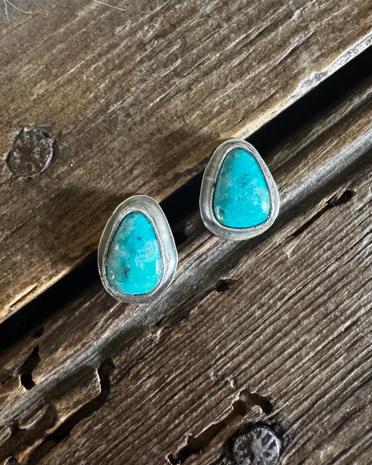 Turquoise stone earrings on a wooden surface