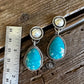 Pair of earrings with turquoise stones and pearl-like centers on a wooden surface with a ruler for scale.